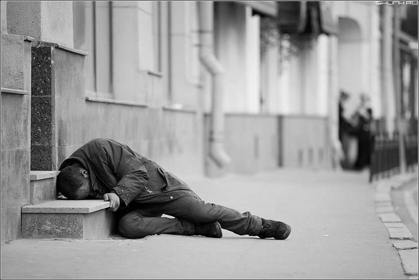 Несчастье равнодушно. Человек лежит на тротуаре. Грустные люди на улице. Мужчина валяется на улице.
